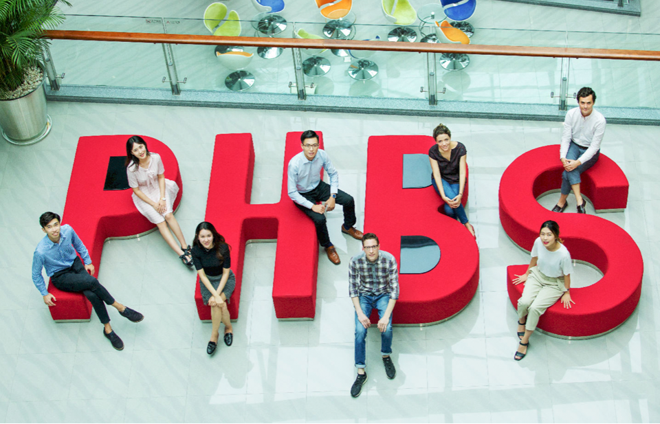 A group of cheerful international students sitting comfortably on a sofa arranged in the shape of the PHBS logo. They are happily smiling and posing for the camera, reflecting the diverse and inclusive community at Peking University HSBC Business School. 